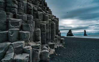 The striking basalt columns of Reynisfjara Beach rise beside the Atlantic Ocean and Reynisdrangar Sea Stacks.