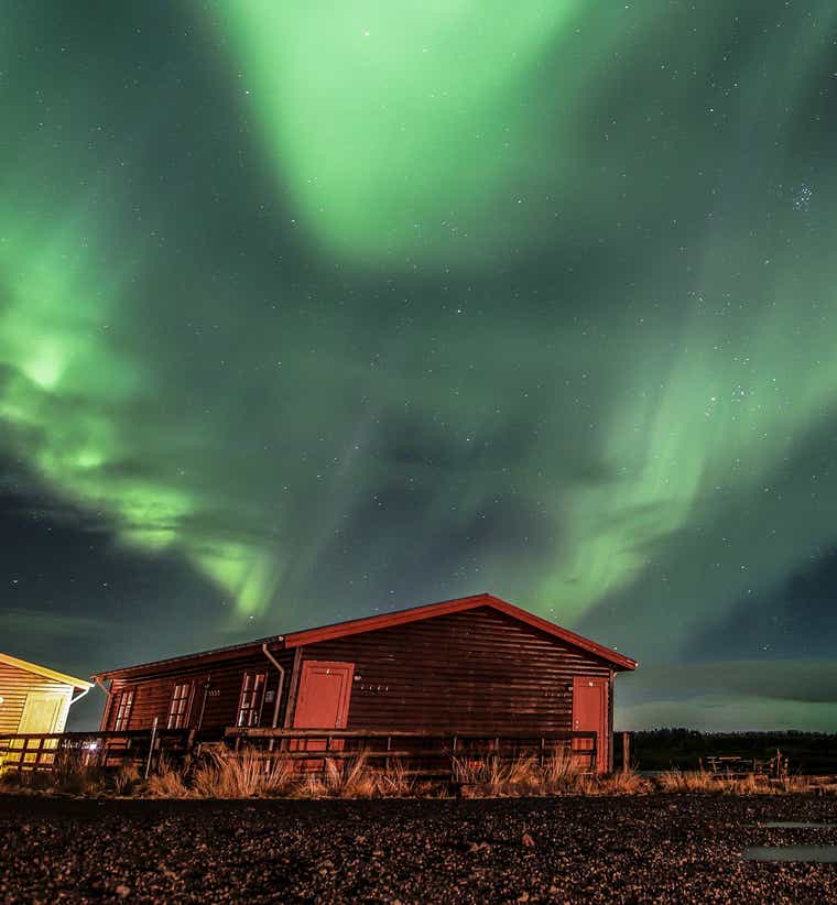 A countryside guesthouse near Hella, Iceland, under the northern lights.