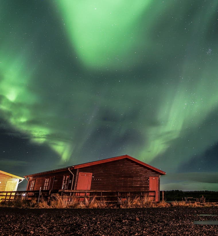 A countryside guesthouse near Hella, Iceland, under the northern lights.