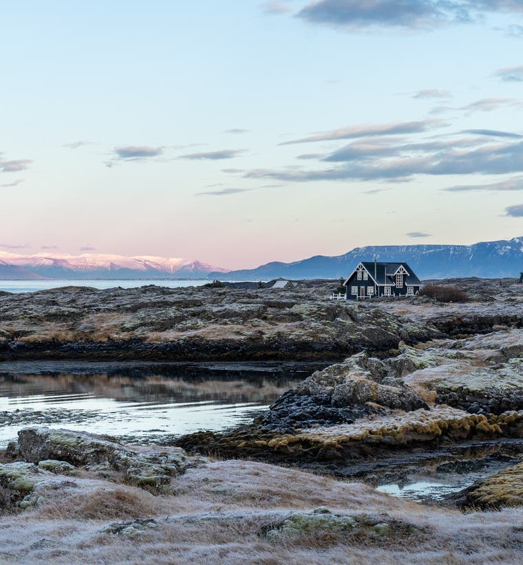 Rocky lava coastline at Vogar on the Reykjanes Peninsula with mountain views across Faxafloi Bay..