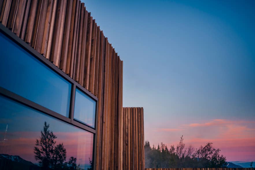Die Holzverkleidung und großen Fenster des Saunagebäudes der Forest Lagoon in der Abenddämmerung