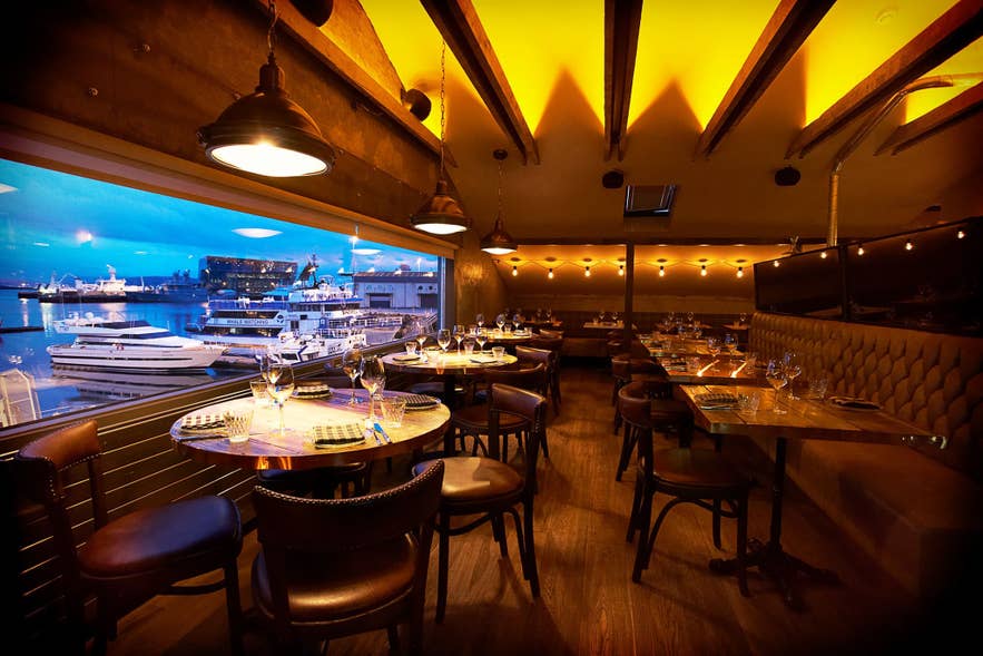 Kopar Restaurant interior with large glass windows overlooking Reykjavik Old Harbour.