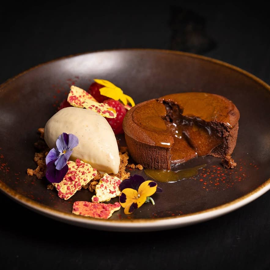 Molten chocolate cake with ice cream and edible flowers, a signature dessert at Sjávargrillið.