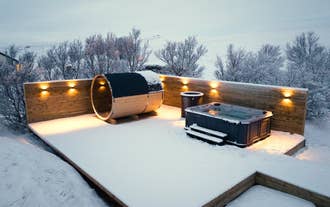 The elegant outdoor spa area at Deluxe Lodge, complete with a sauna, jacuzzi, and cold tub, covered in a blanket of snow.