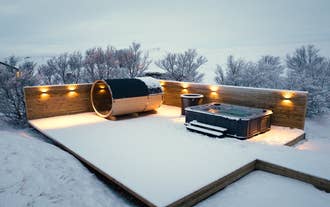 L’élégant espace spa extérieur de Deluxe Lodge, avec sauna, bain chaud et bassin froid, sous un manteau de neige.