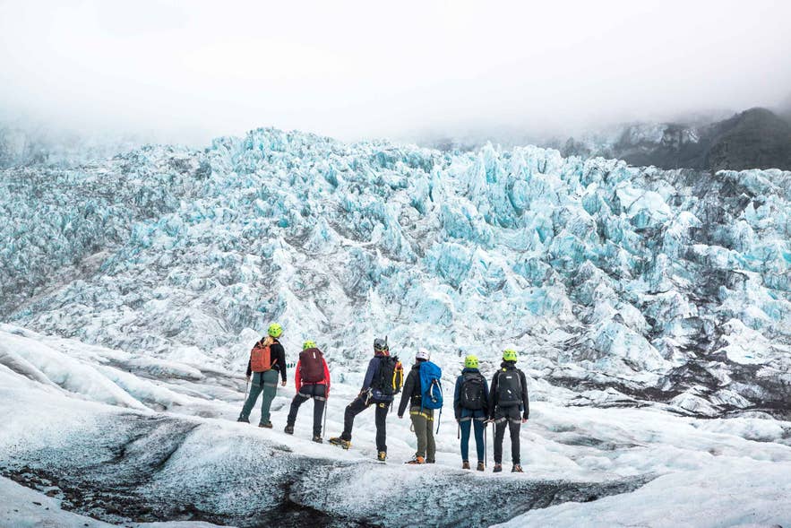 A group in red jackets hiking on a glacier in Iceland in low cloud