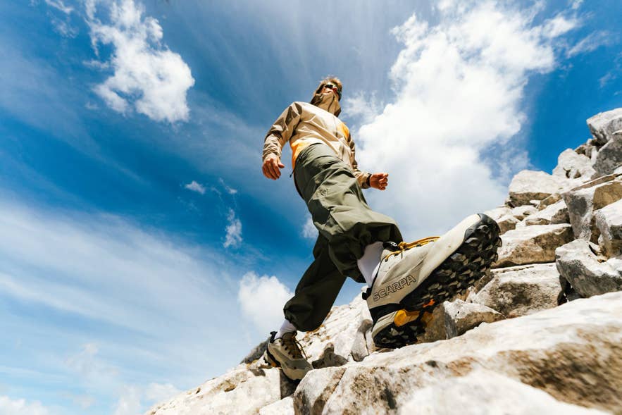 Close-up of a person wearing sturdy hiking shoes while standing on rocky Icelandic terrain.