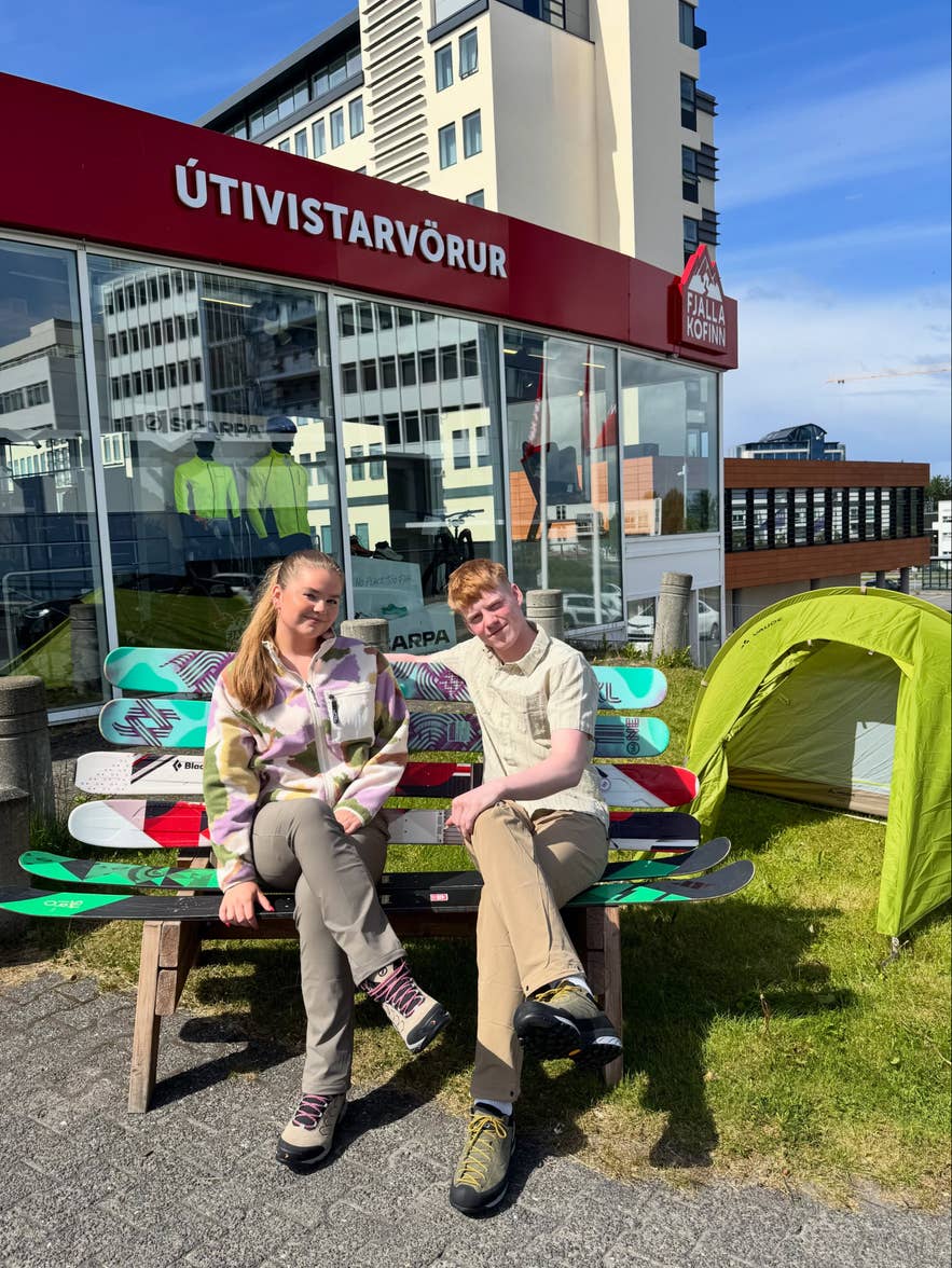 Two people posing together outside the Fjallakofinn outdoor store in Reykjavik.