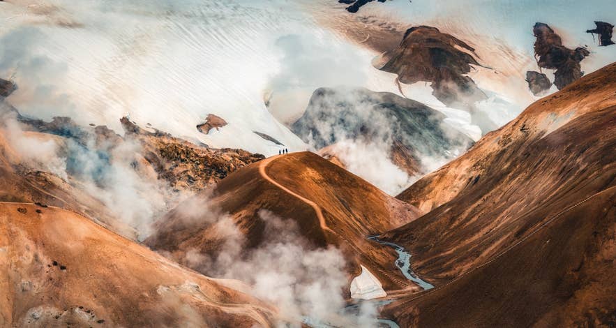 Hikers on a ridge above steaming vents in the Hveradalir geothermal area of Kerlingarfjoll in the Icelandic Highlands.