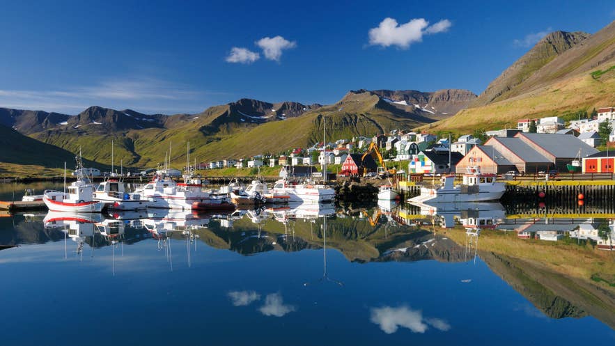 Ships and boats at a harbor in Iceland with mountains in the background.
