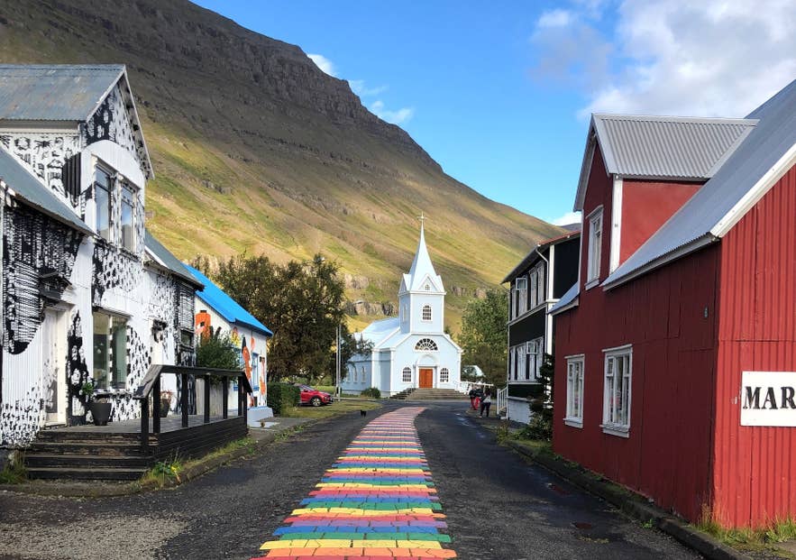 The Rainbow Street leading to the blue church in Seydisfjordur, a colorful town in East Iceland.