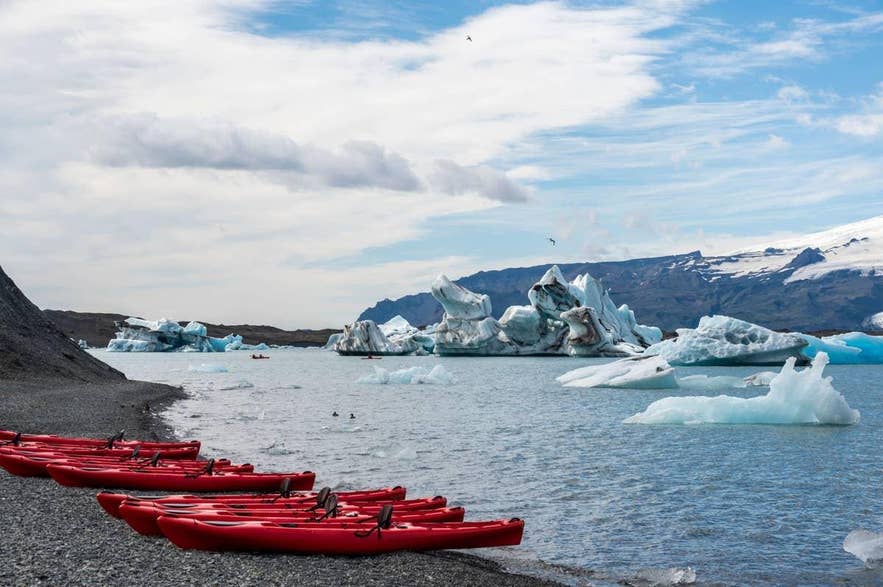 Red kayaks lined up on the shore of an iceberg-filled glacier lagoon Red kayaks lined up on the shore of an iceberg-filled glacier lagoon