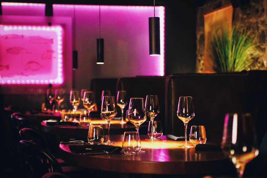 Dining tables set with wine glasses under pink lighting inside Matarkjallarinn in Reykjavik