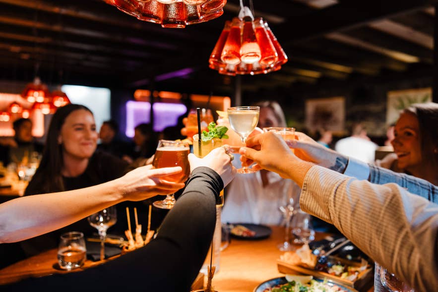 Group of diners raising drinks for a toast inside Matarkjallarinn restaurant