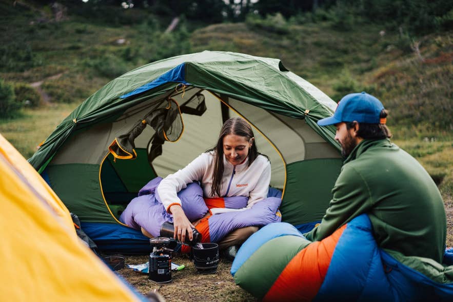 Two friends brewing coffee inside a tent while camping in the Icelandic Highlands.