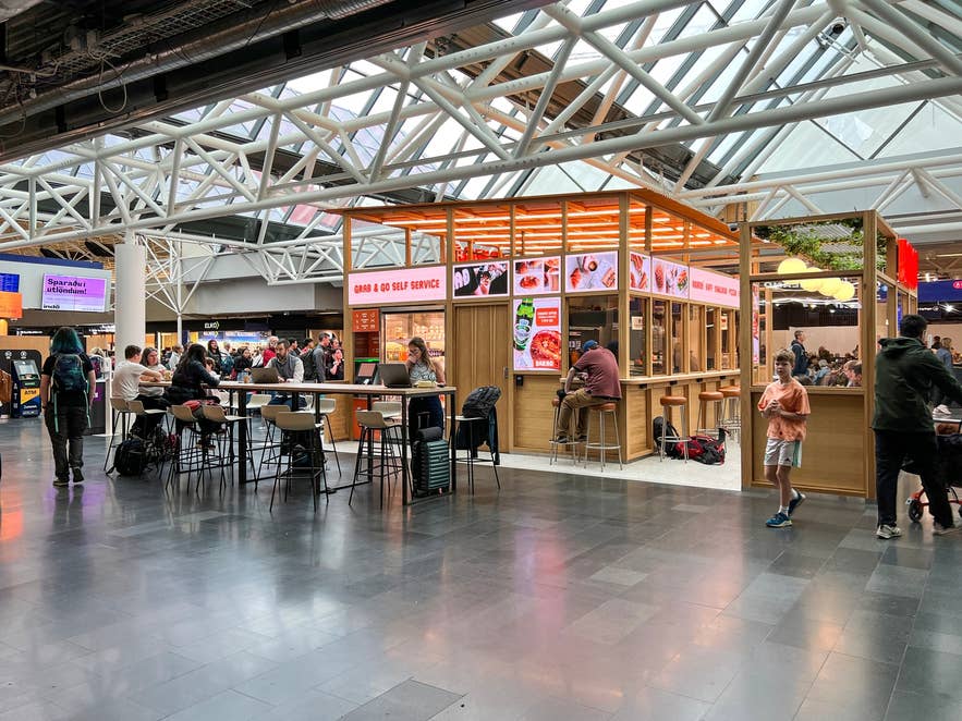 Travelers sit at a food court in the departure hall of Keflavik International Airport before their flights. Travelers sit at a food court in the departure hall of Keflavik International Airport before their flights.