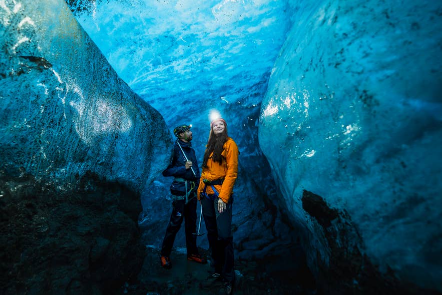 Two travelers with headlamps in a blue ice cave on Arctic Adventures' glacier hike and ice cave tour from Skaftafell.