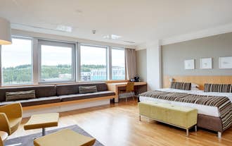 Spacious suite with a double bed and a long window bench overlooking Reykjavik from Oskjuhlid.