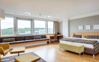 Spacious suite with a double bed and a long window bench overlooking Reykjavik from Oskjuhlid.