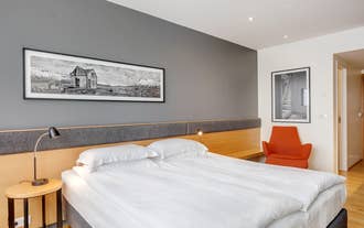 Double bed with crisp white linen below a framed Iceland landscape print in a Reykjavik hotel.