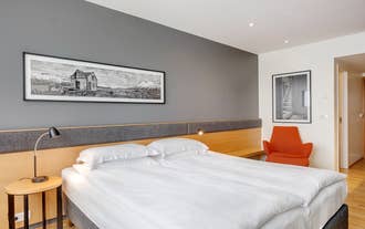Double bed with crisp white linen below a framed Iceland landscape print in a Reykjavik hotel.