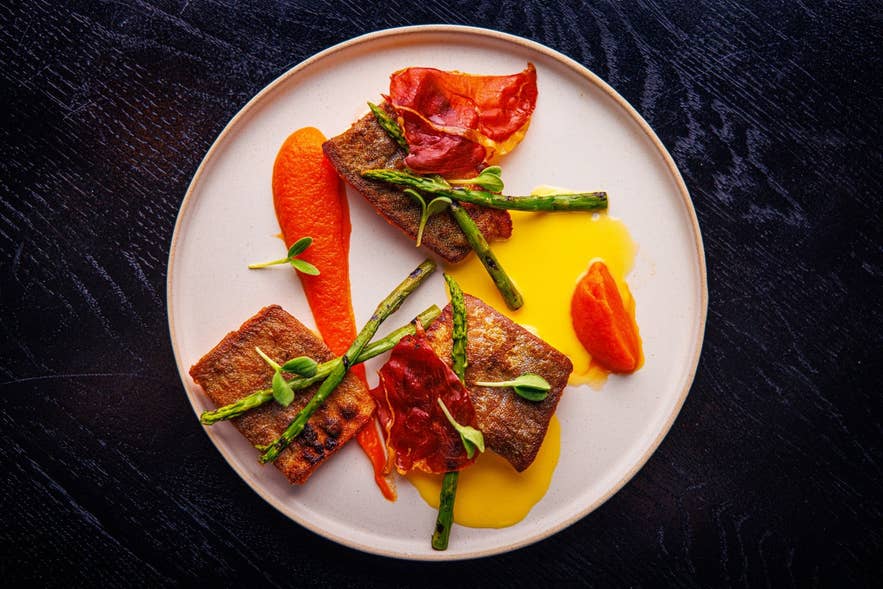 Plated fish main course with asparagus and carrot puree at Mulaberg Bistro and Bar in Akureyri.