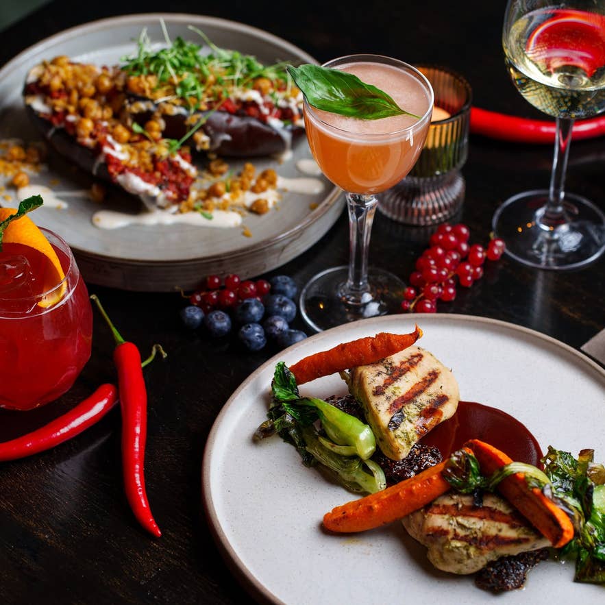Grilled chicken, salmon, and cocktails on a dark table at Mulaberg Bistro and Bar in Akureyri.