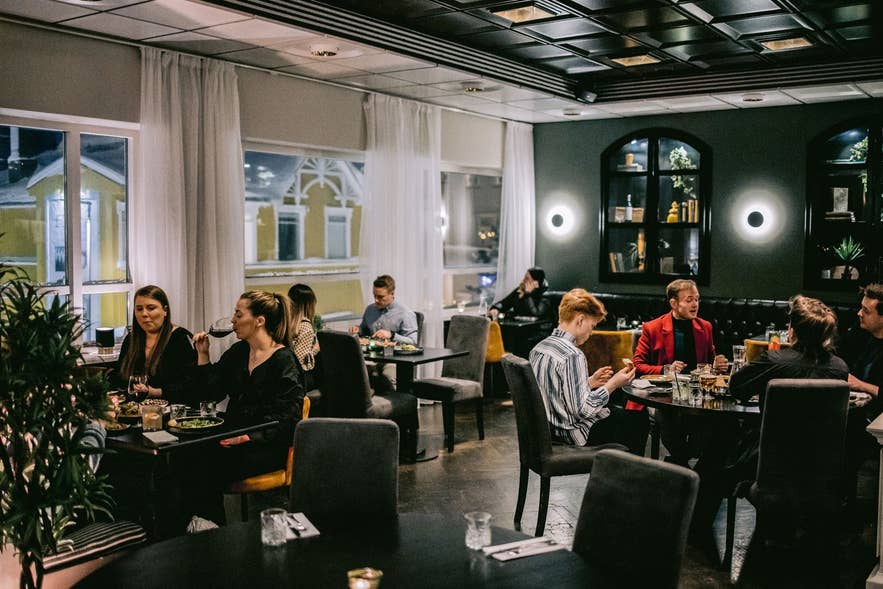 Guests dining in the dark green dining room at Mulaberg Bistro and Bar inside Hotel KEA in Akureyri.