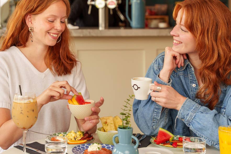 Two friends sharing brunch plates, coffee, and juice at Terian Brasserie in Akureyri