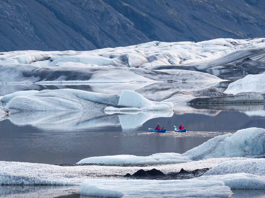 Two kayakers paddling among icebergs at Heinabergslon Glacier Lagoon in Vatnajokull National Park.