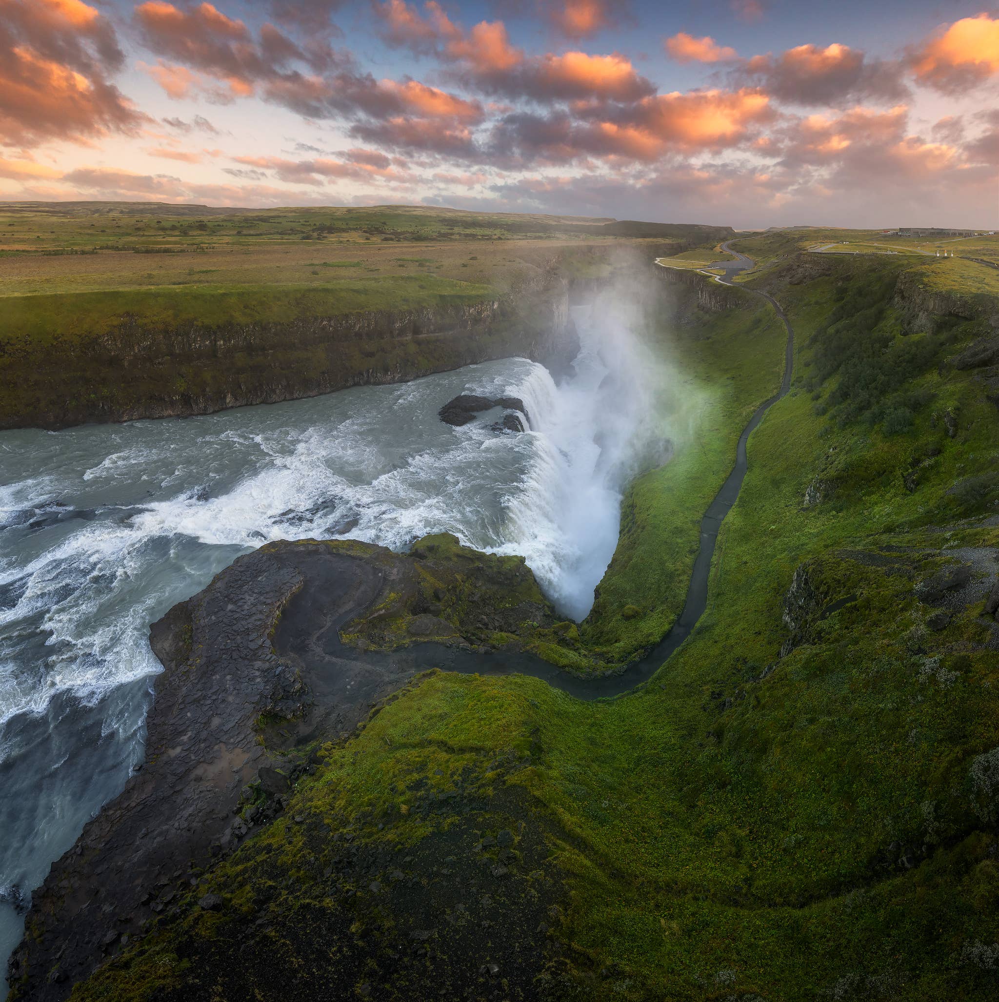 Gullfoss Waterfall drops into a deep, green canyon under a sunset sky on the Golden Circle route.