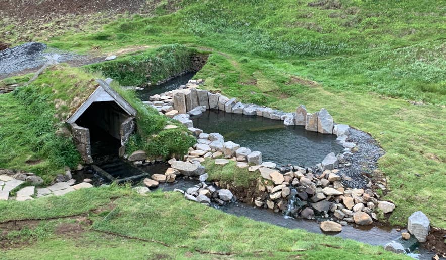 Turf-roofed hut and stone-edged pool at Hrunalaug Hot Spring near Fludir