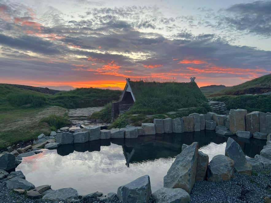 Sunset over the basalt-ringed pool and turf hut at Hrunalaug Hot Spring