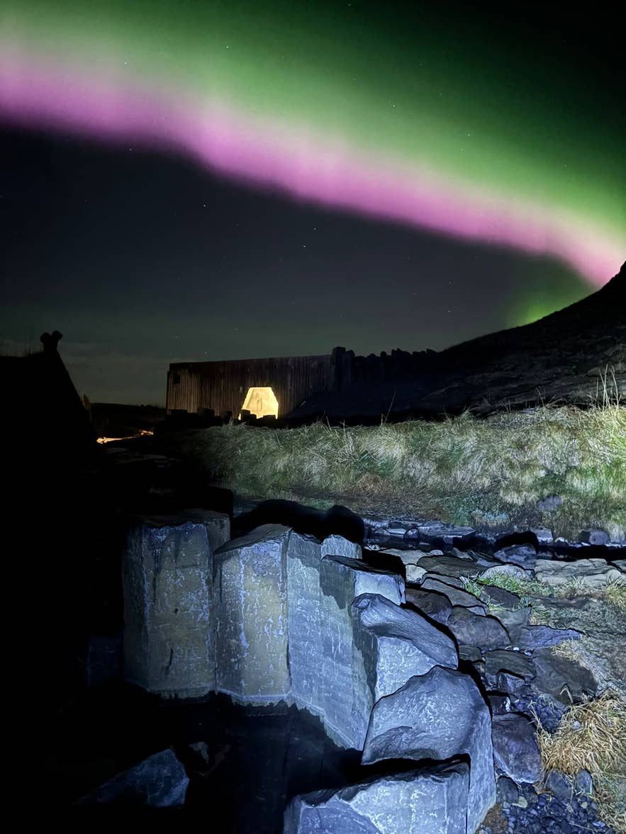 Northern lights over the basalt pool edge at Hrunalaug Hot Spring at night
