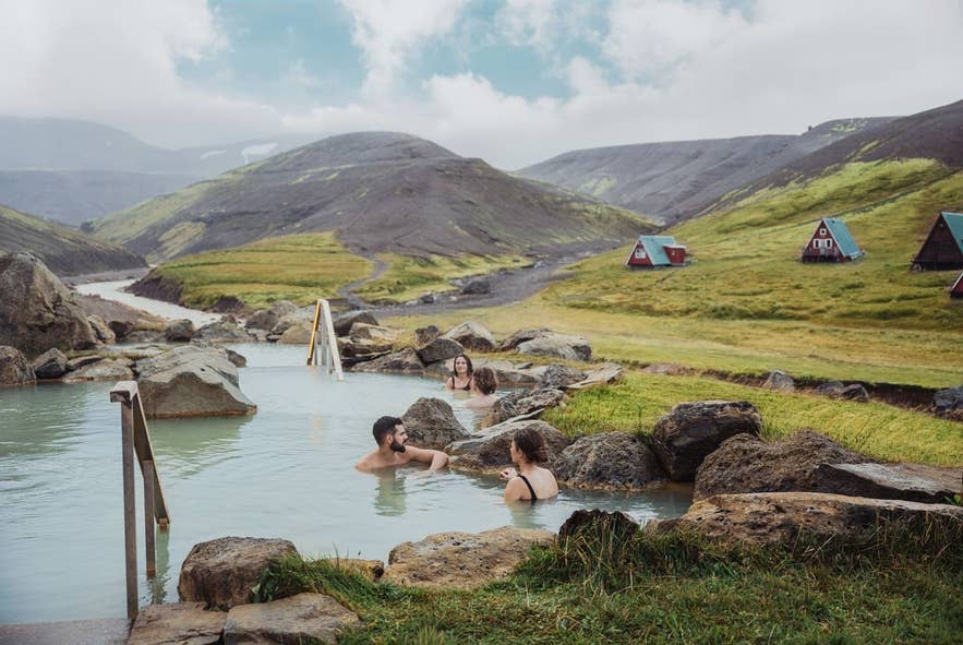 Bathers in the Highland Baths geothermal pool at Highland Base, Kerlingarfjöll, with A-frame huts behind