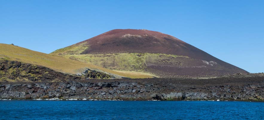 Eldfell volcano above the black 1973 lava shore of Heimaey, seen from the sea