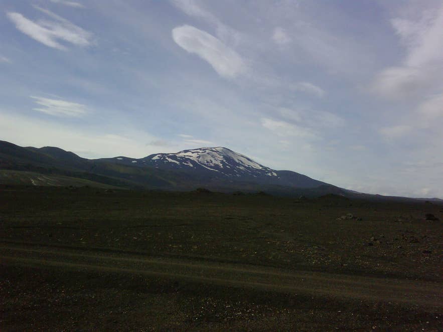Snow-streaked Hekla volcano seen across lava and gravel from the F225 track by the Nýjahraun lava field Snow-streaked Hekla volcano seen across lava and gravel from the F225 track by the Nýjahraun lava field