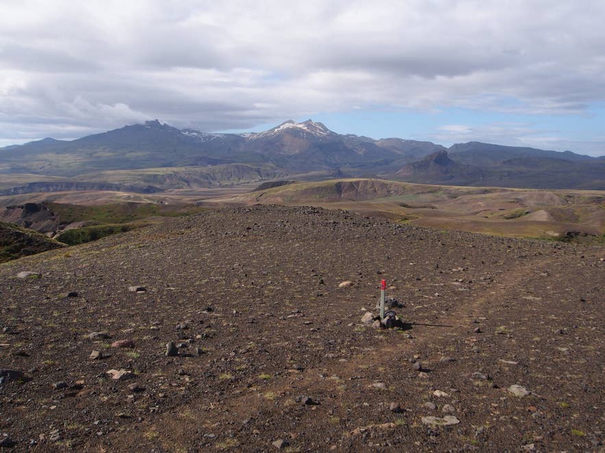 Trail marker on gravel ground east of Tindfjöll on the Tindfjallahringur loop, Tindfjallajökull behind