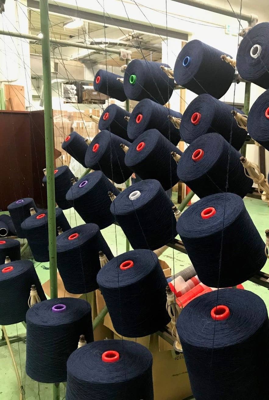 Cones of dark blue lopi wool yarn inside the Ístex factory