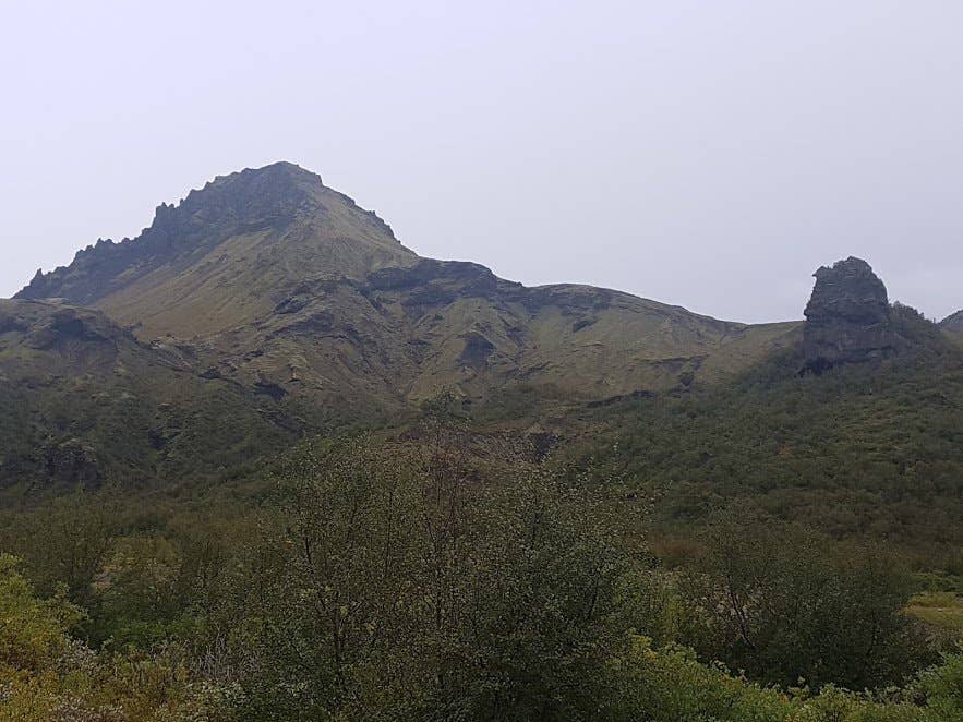 The jagged rocky crest of Útigönguhöfði mountain seen from the Goðaland birch woods on a grey day