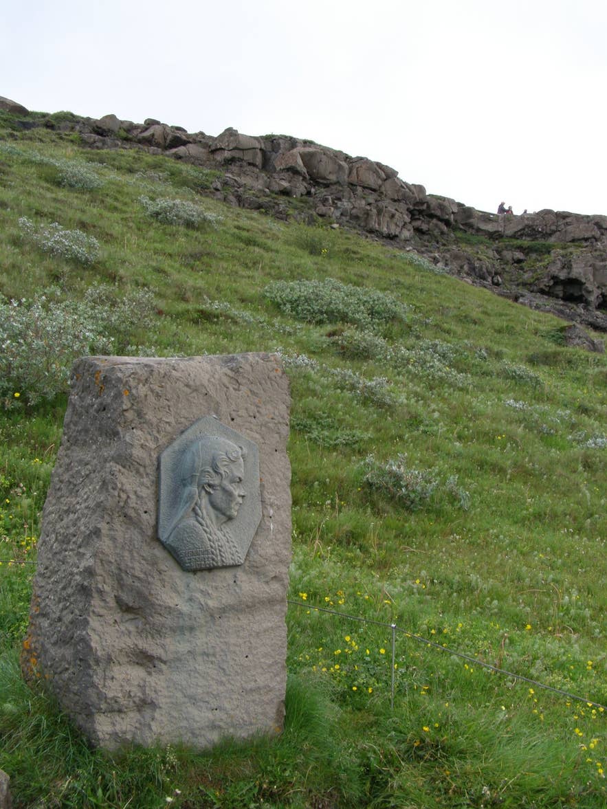 Basalt memorial stone with bronze relief of Sigríður Tómasdóttir on the grassy slope at Gullfoss