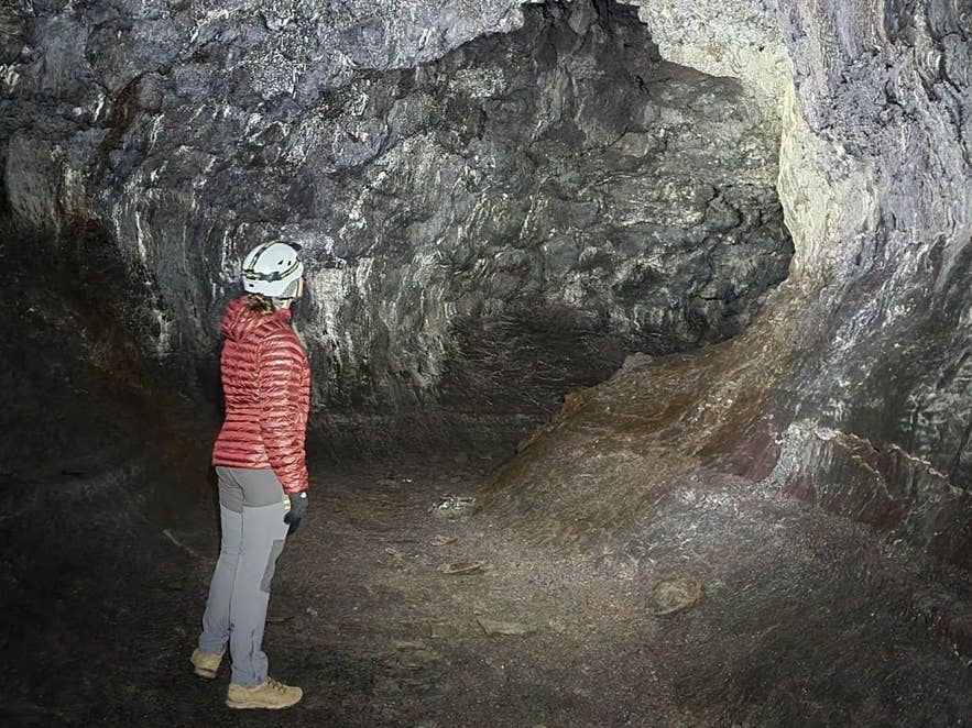 Guide in a helmet inside Borgarhellir lava cave, Gullborgarhraun