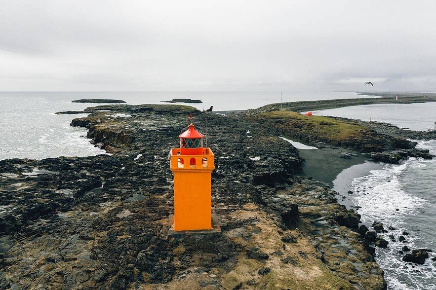 Hvanneyjarviti lighthouse, a yellow-painted concrete tower with a red lantern, at the east end of Hvanney near Höfn