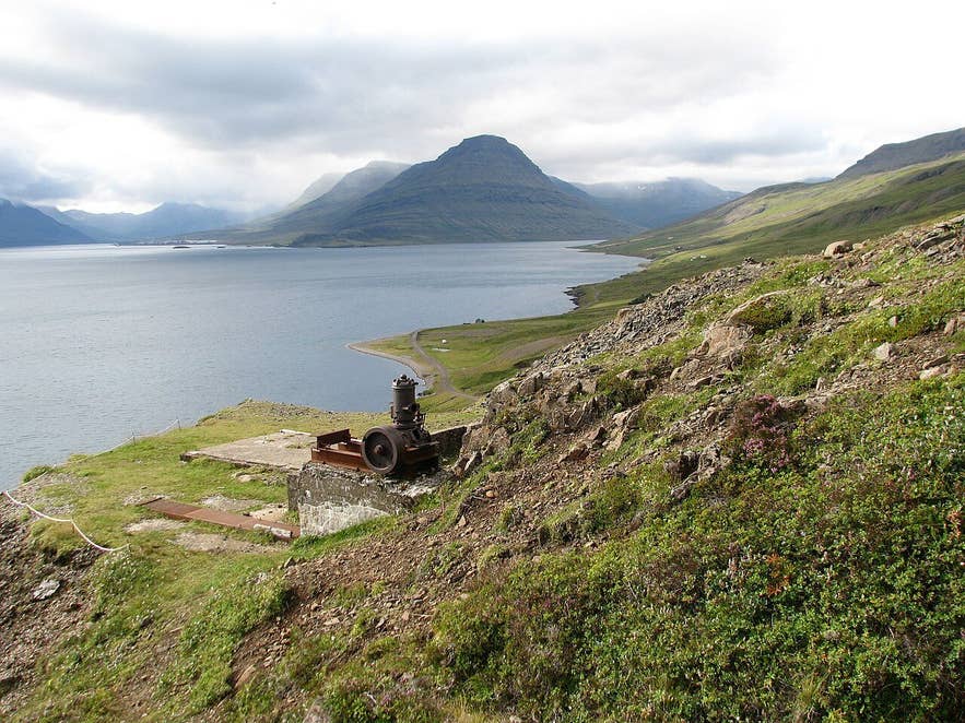 Rusting mining machinery at Helgustaðanáma with Reyðarfjörður fjord behind