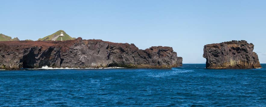 Urðaviti lighthouse and the eastern edge of the Eldfell lava seen from a boat off Heimaey Urðaviti lighthouse and the eastern edge of the Eldfell lava seen from a boat off Heimaey