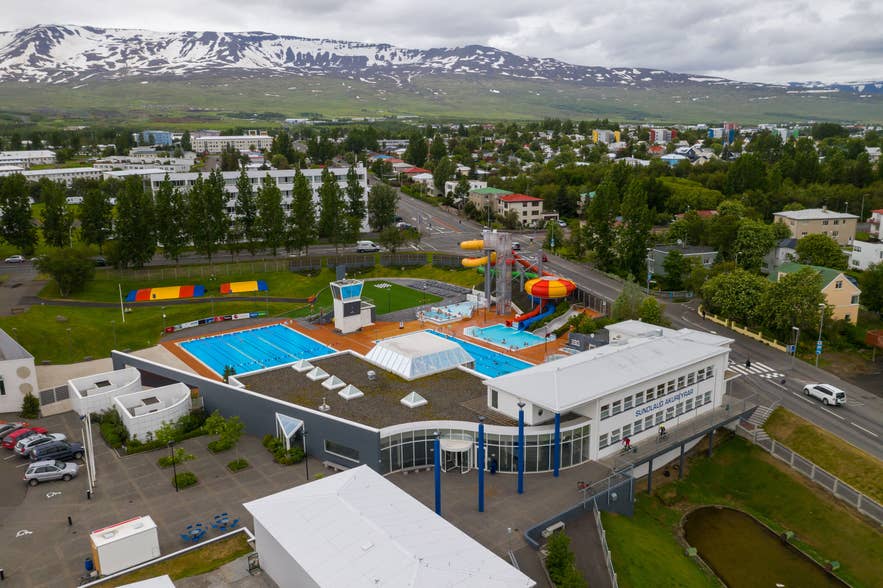 Vue aérienne d’Akureyri Swimming Pool avec ses bassins de nage et ses toboggans aquatiques au pied de montagnes enneigées. Vue aérienne d’Akureyri Swimming Pool avec ses bassins de nage et ses toboggans aquatiques au pied de montagnes enneigées.