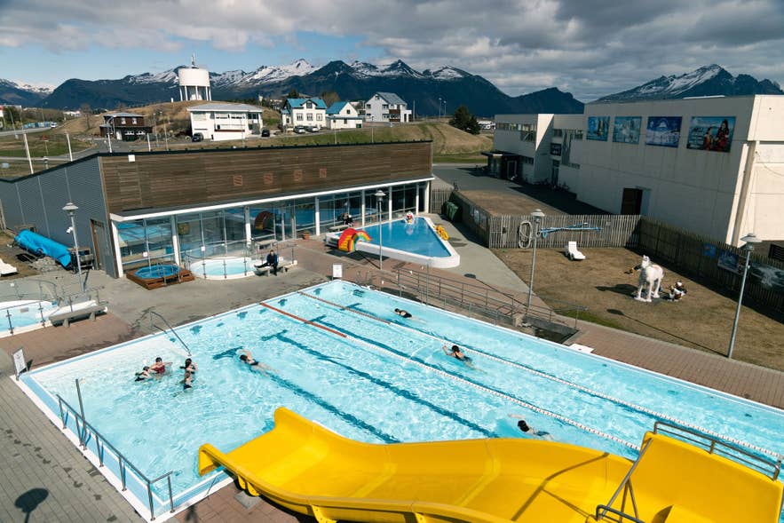 La piscine de Höfn avec son toboggan aquatique jaune, son bassin de nage et les montagnes en arrière-plan. La piscine de Höfn avec son toboggan aquatique jaune, son bassin de nage et les montagnes en arrière-plan.