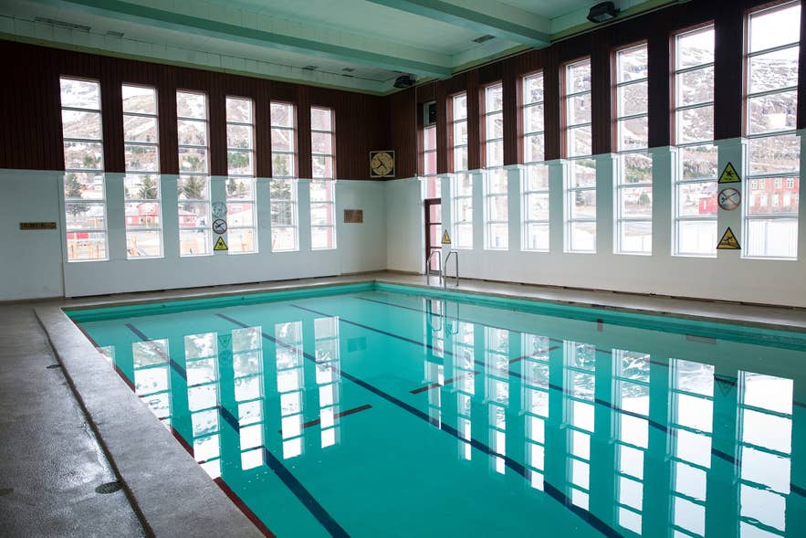 The indoor lane pool at Sundholl Seydisfjardar, lit by tall windows facing the mountains.
