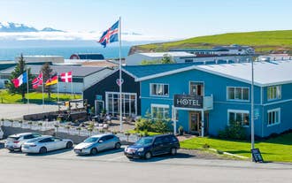 Blue facade of a hotel in Husavik with flags out front and Skjalfandi Bay in the distance in North Iceland.
