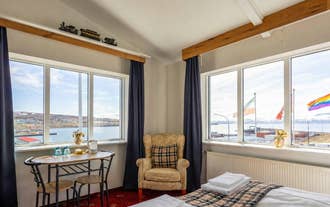 Suite lounge with a table by wide windows facing Skjalfandi Bay in Husavik, North Iceland.